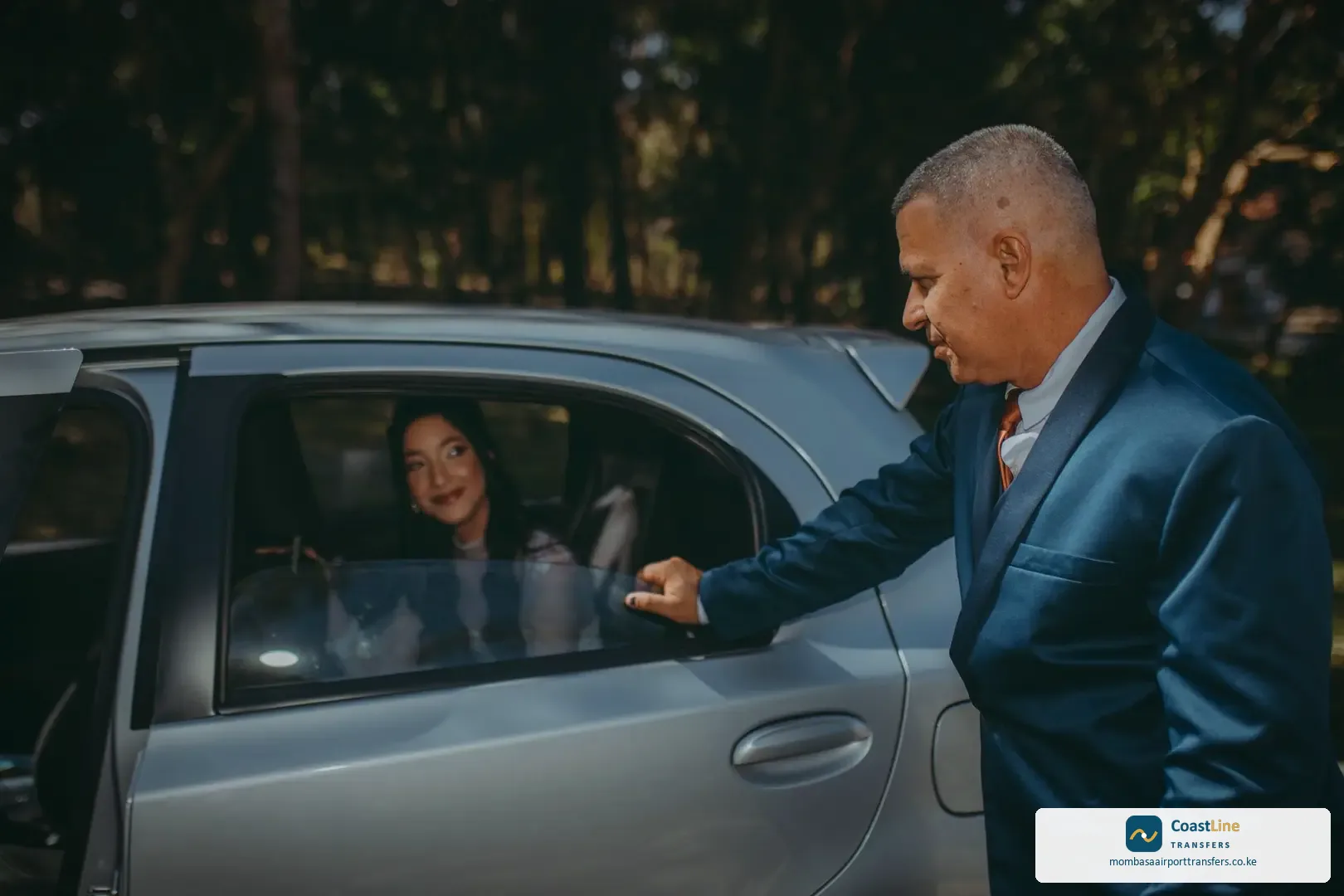 professional private transfer driver standing beside executive sedan at airport terminal